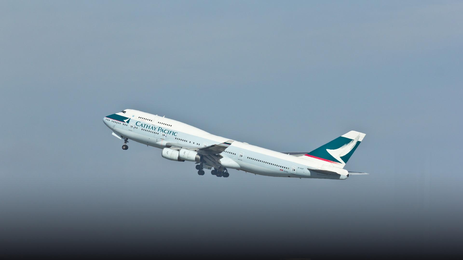 A Cathay Pacific Boeing 747-400 jumbo jet climbing majestically into the sky with landing gear retracted.