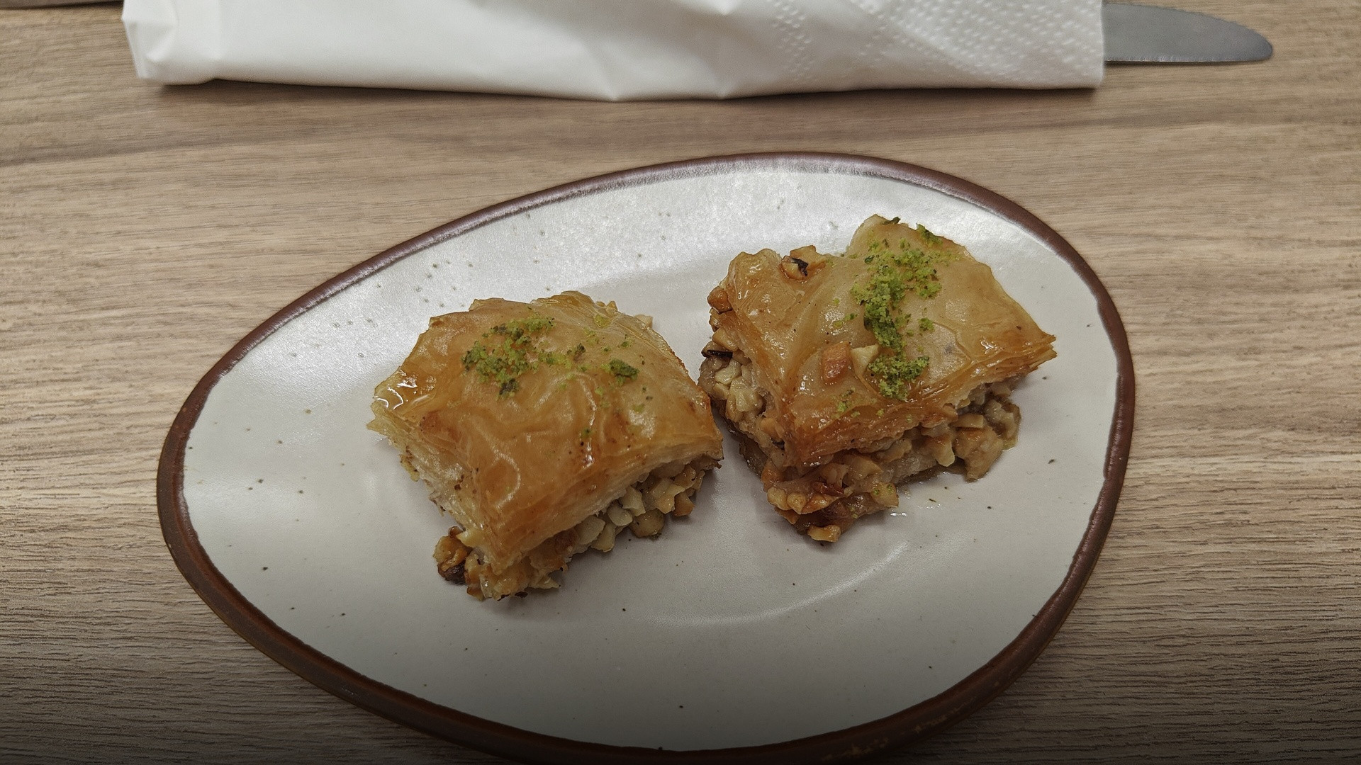 Glistening diamond-cut pieces of golden layered Baklava pastry topped with finely crushed pistachios.