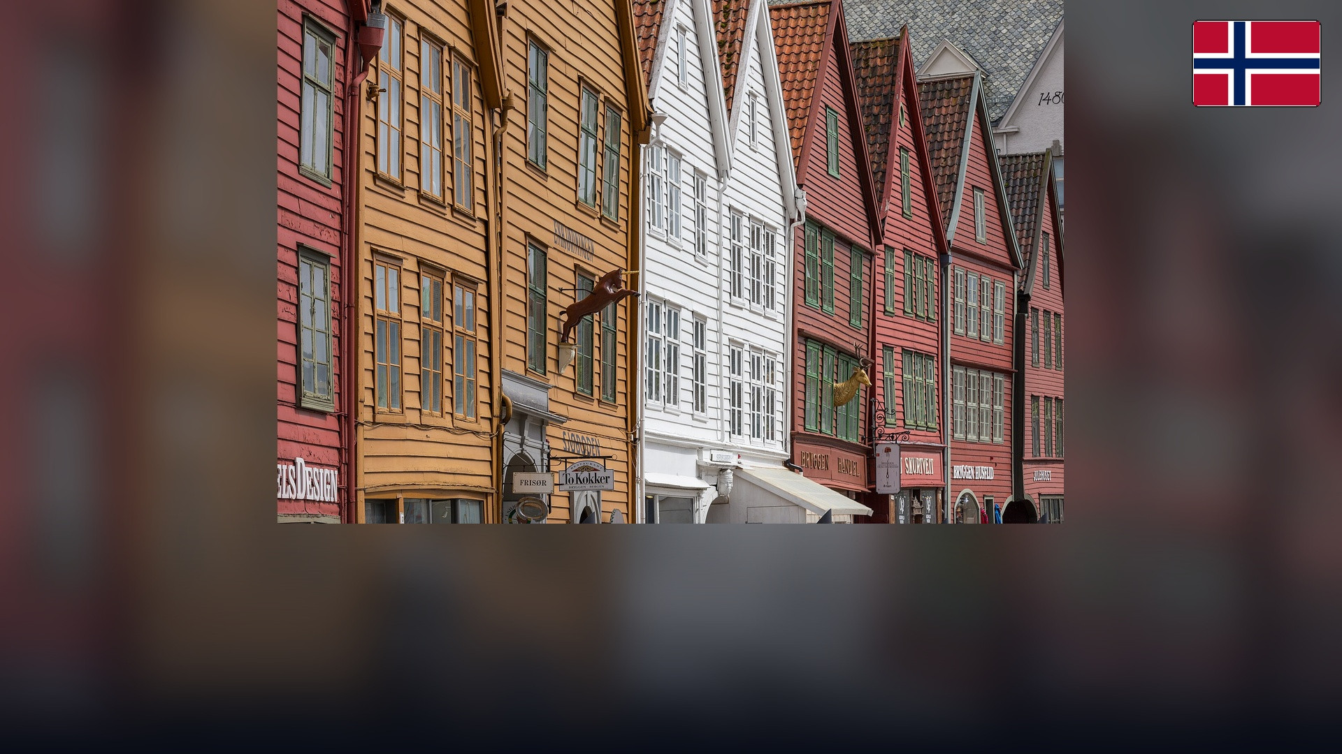 Historic wooden Bryggen waterfront in Bergen with the Norwegian flag in the top right corner.