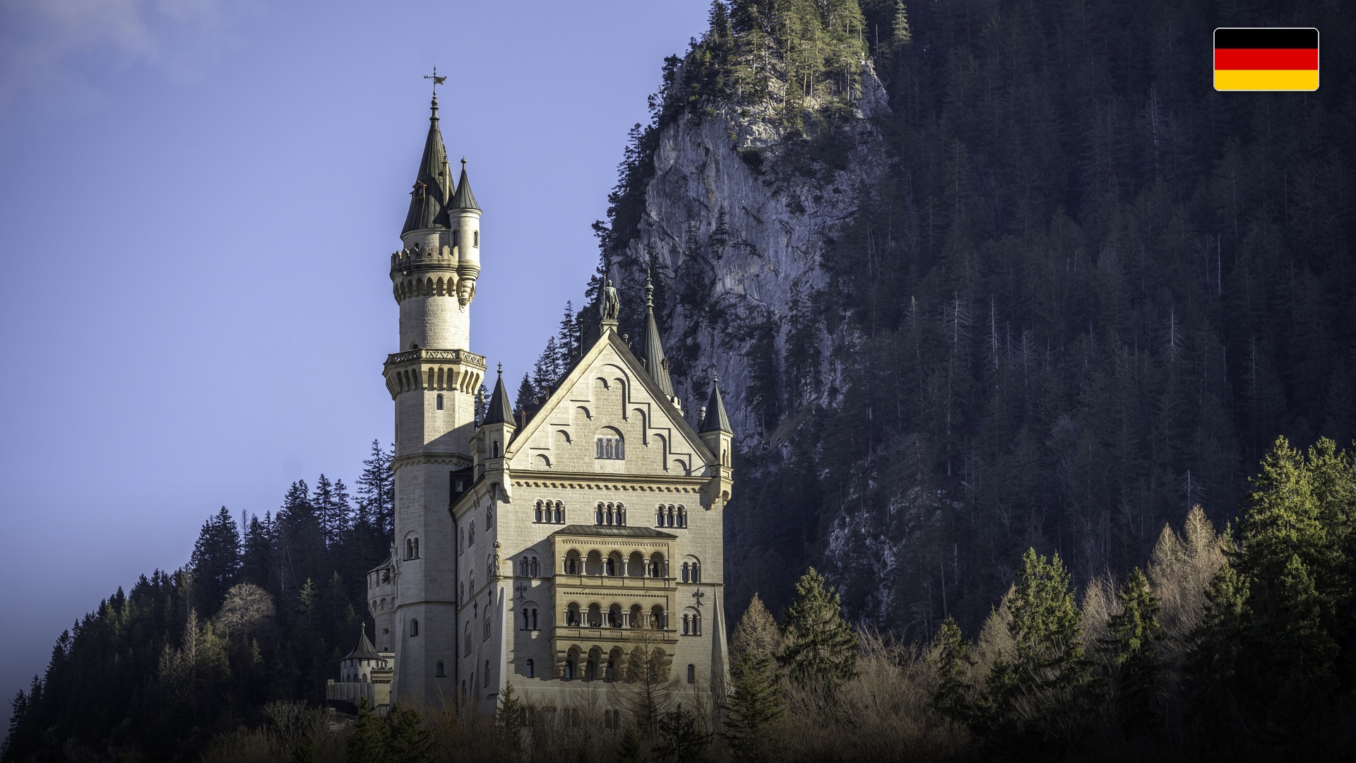 Fairy-tale Neuschwanstein Castle perched on a rugged alpine cliff against green Bavarian valleys.