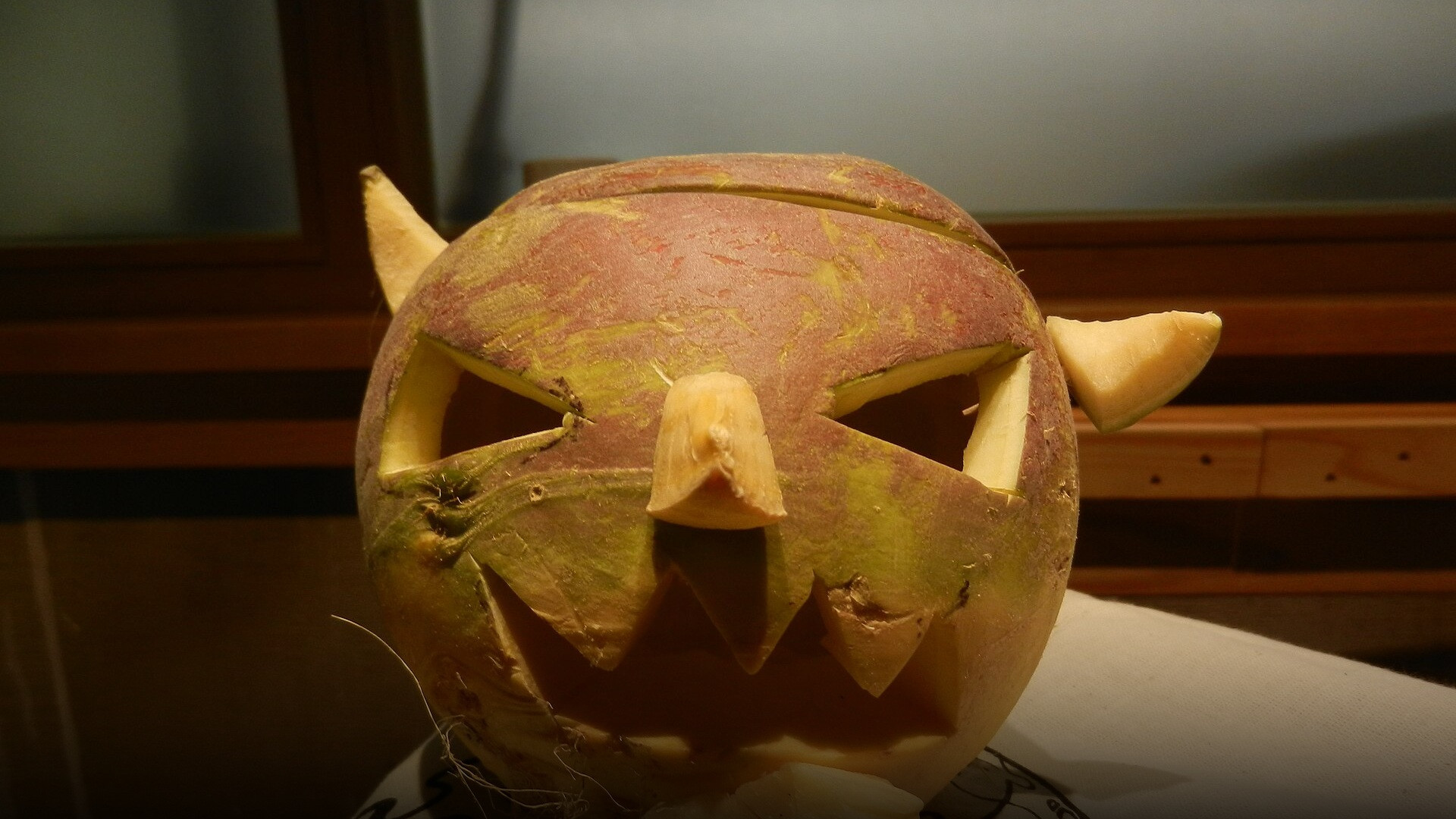 A traditional carved Scottish Samhuinn turnip lantern showing an eerie, demon-like grimace and hollow eyes.