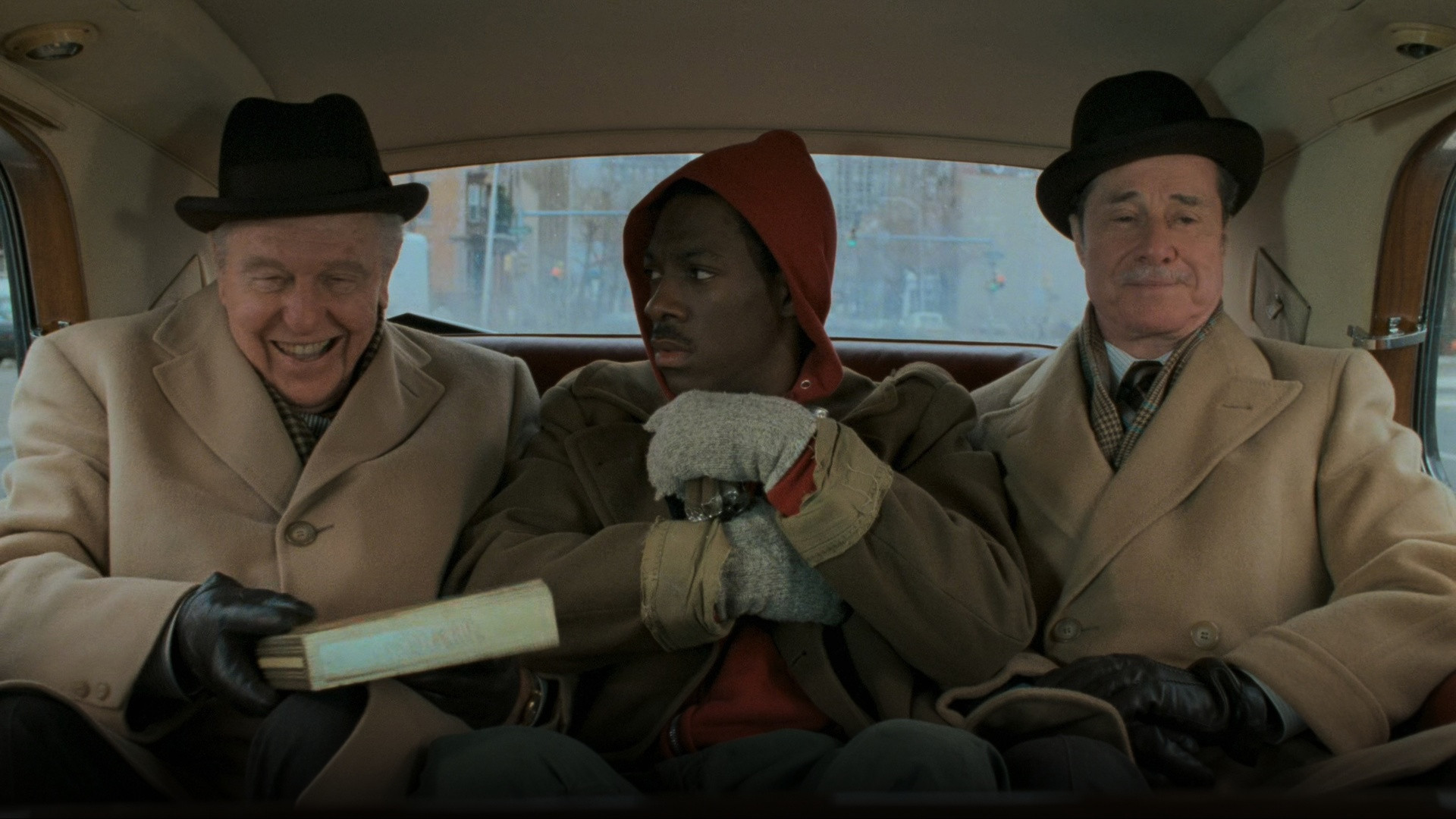 Dan Aykroyd as Louis Winthorpe III and Eddie Murphy as Billy Ray Valentine conferring together on Wall Street in Trading Places.