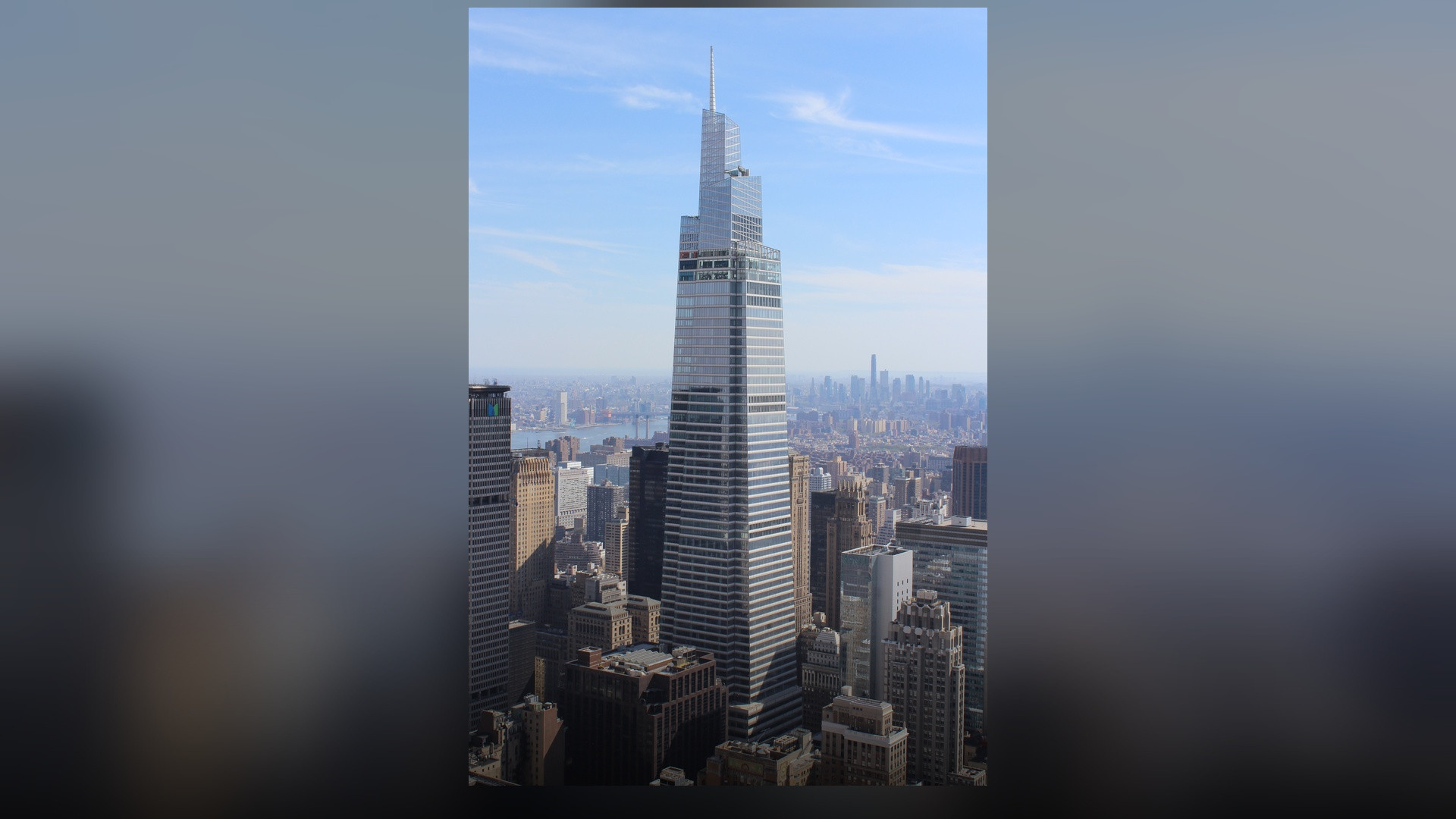 A clean, upright vertical photograph of One Vanderbilt's tapered glass spire and terracotta facade towering over Midtown Manhattan.