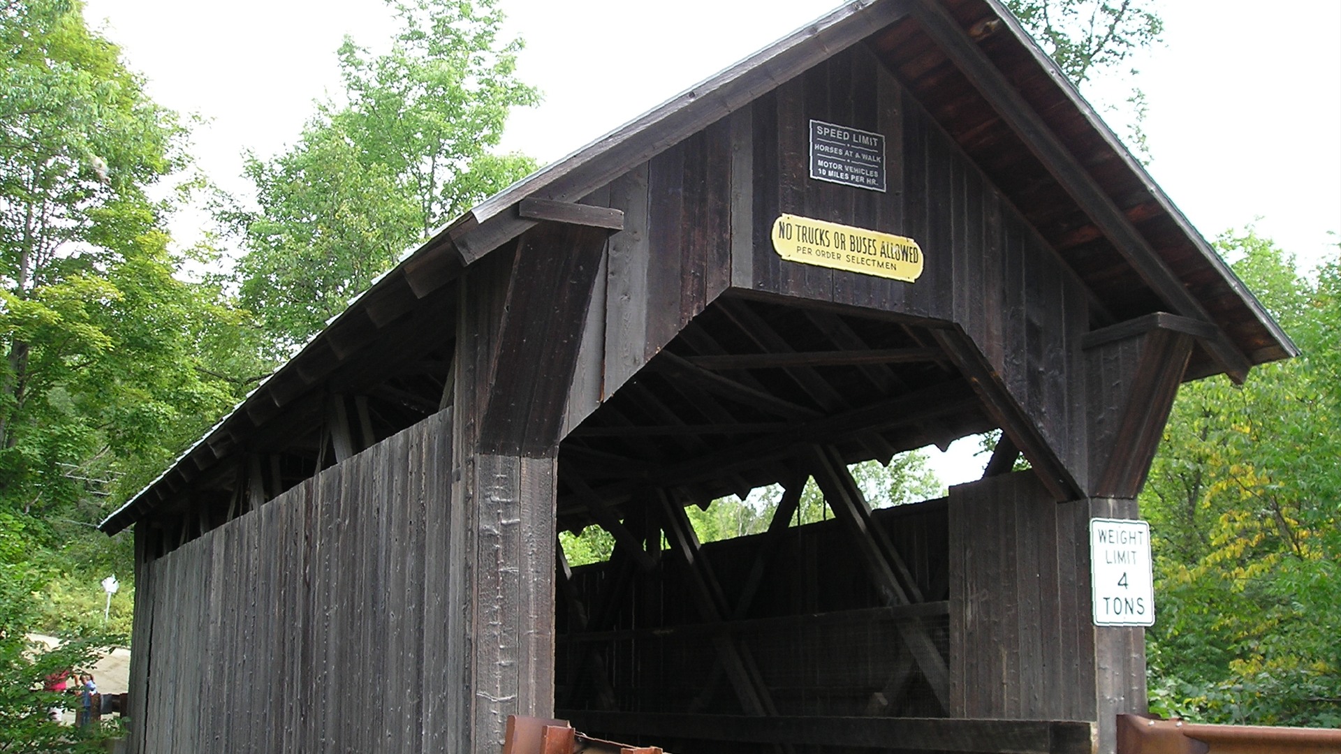 Historic 1844 Gold Brook Covered Bridge surrounded by green trees in Stowe, Vermont