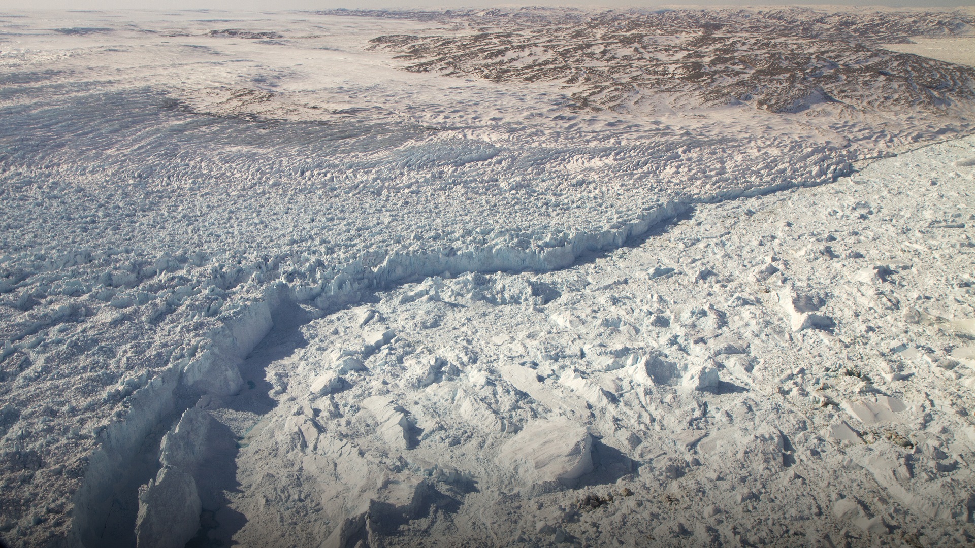 Aerial view of the massive calving front of the Jakobshavn Isbrae glacier discharging colossal icebergs into Ilulissat Icefjord.