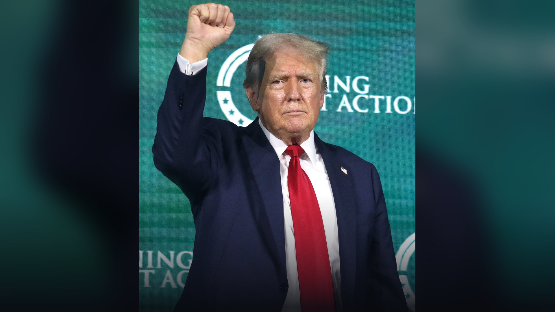 President Donald Trump speaking at a live rally podium.