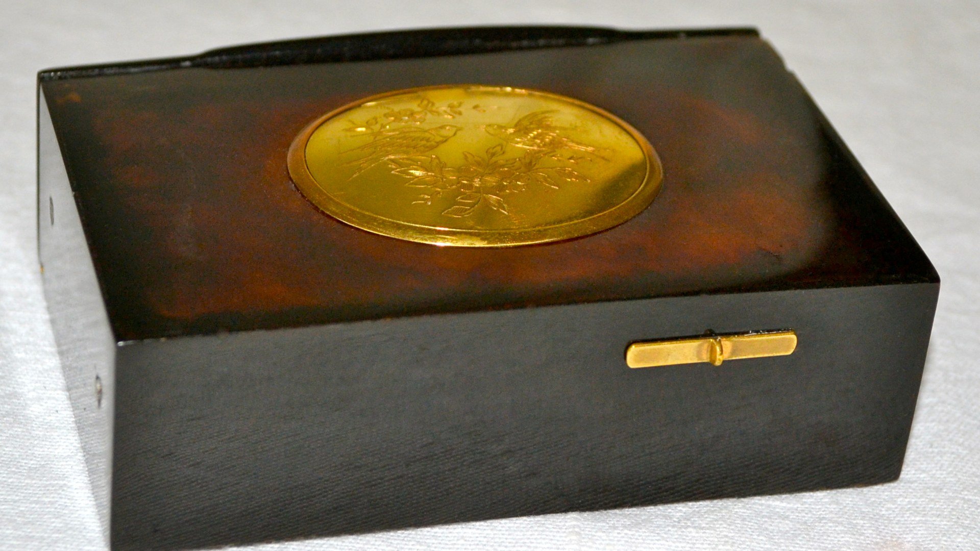 Antique mechanical singing bird box automaton with gold medallion lid.