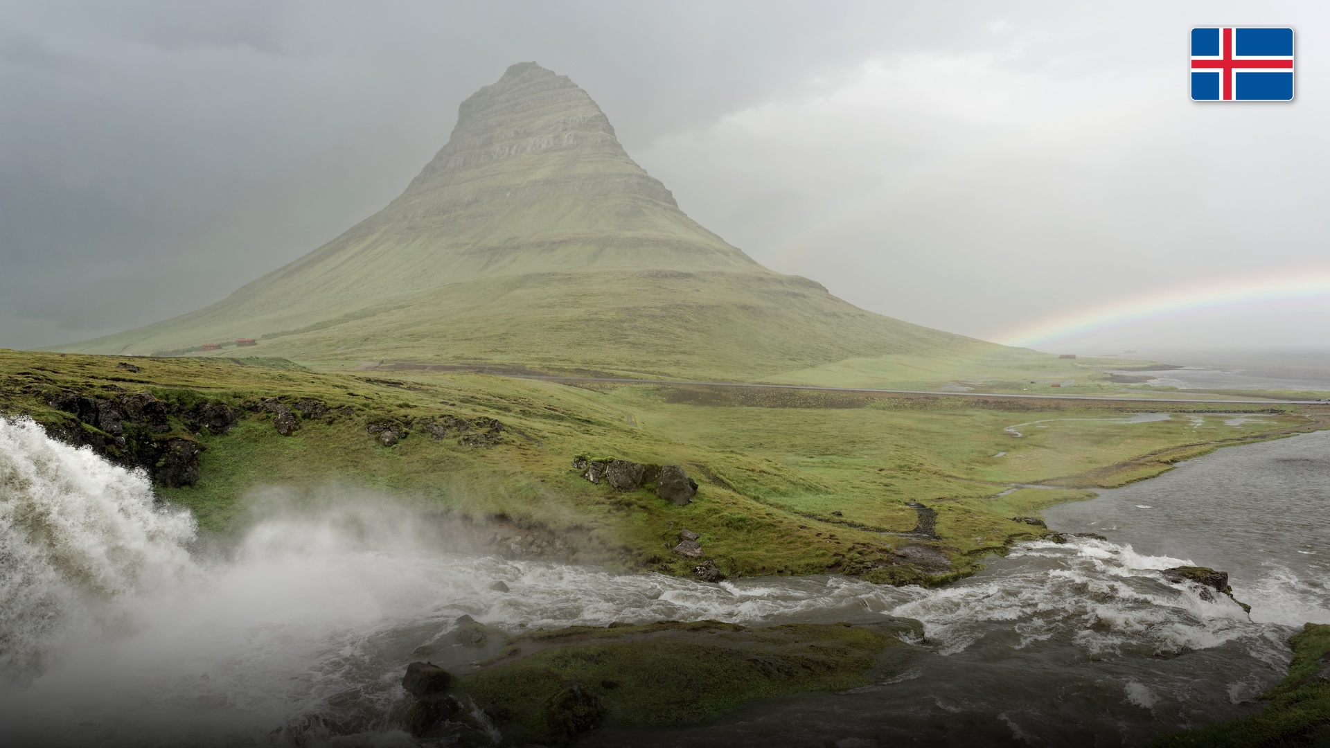 Kirkjufell mountain and cascading waterfalls under soft northern skies in Grundarfjordur.