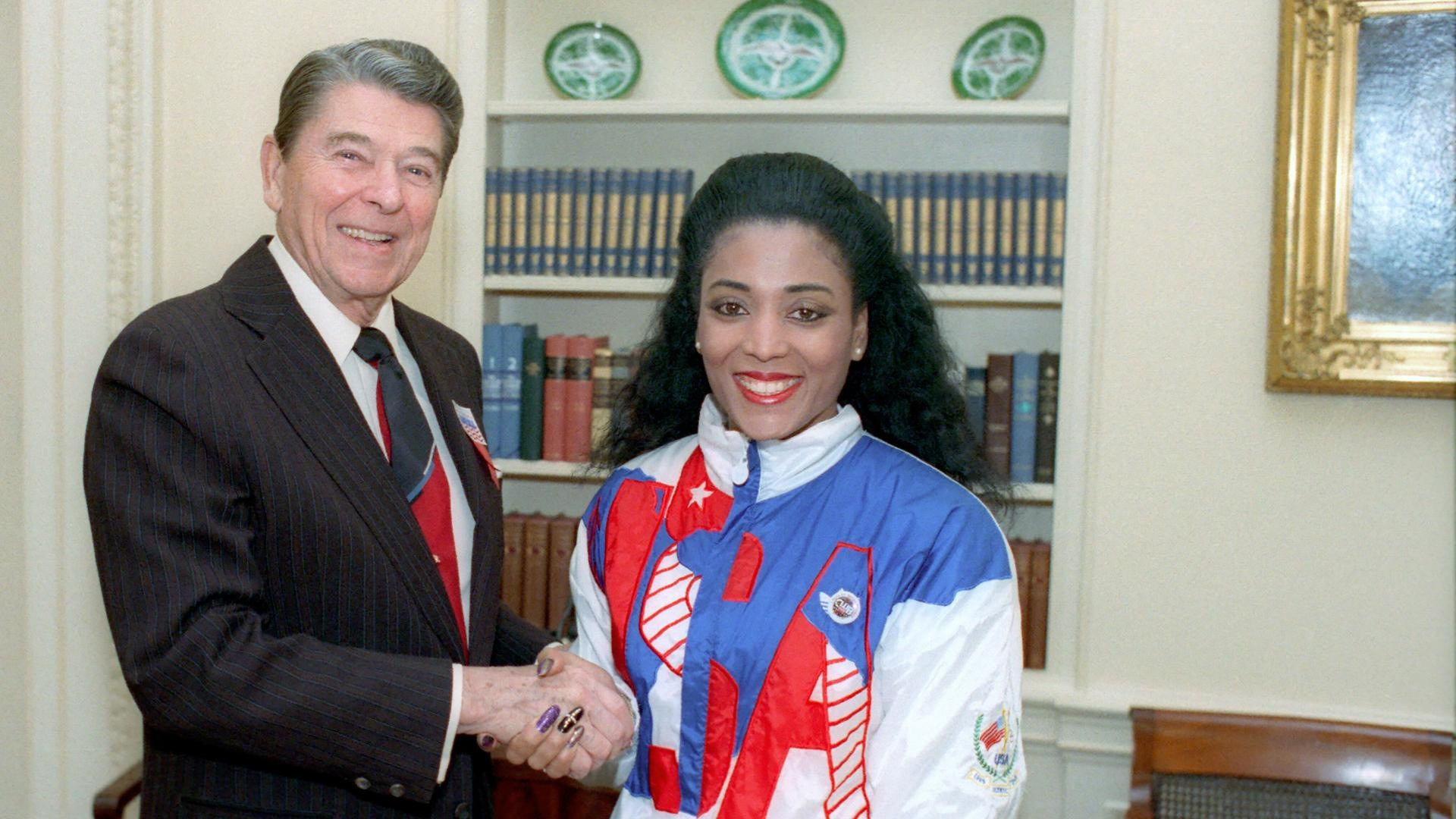 Florence Griffith-Joyner smiling proudly in her USA Olympic team tracksuit.