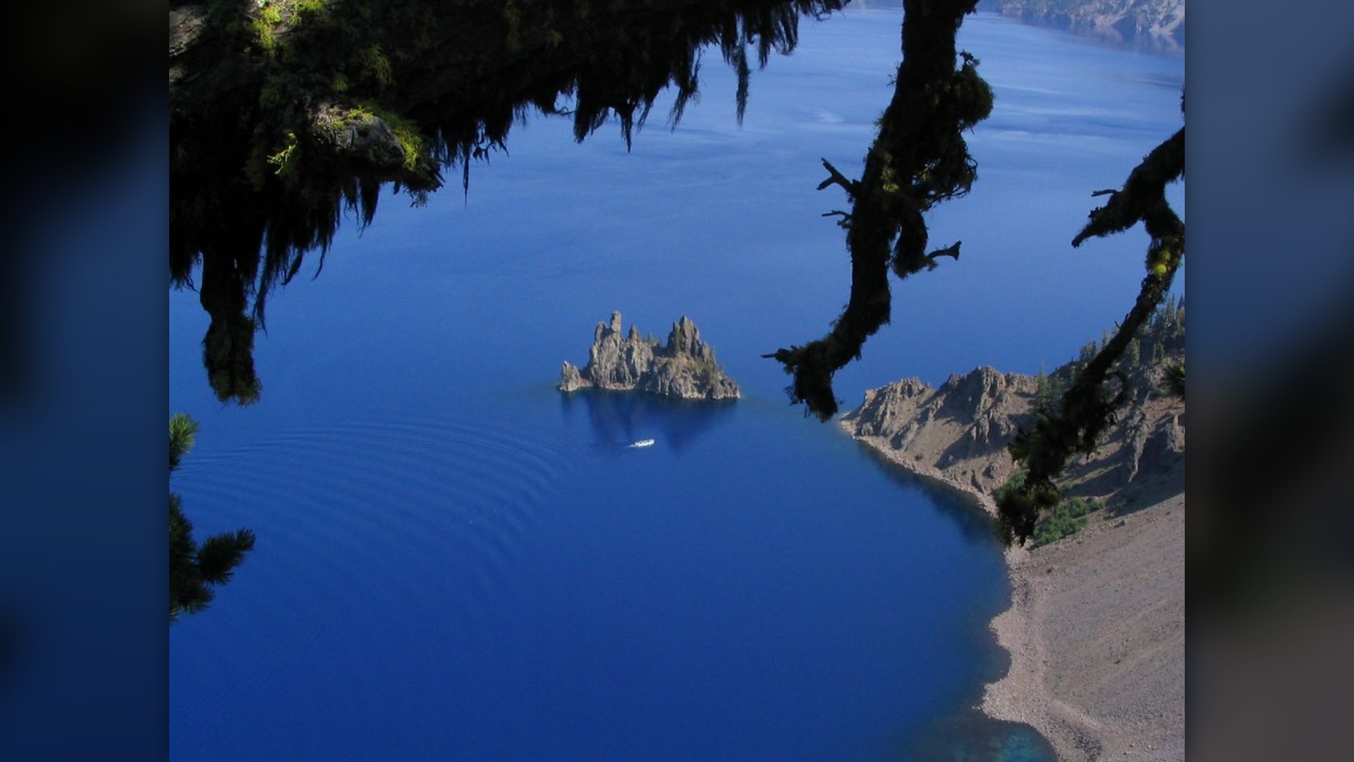 Deep blue water of Crater Lake Oregon surrounded by caldera