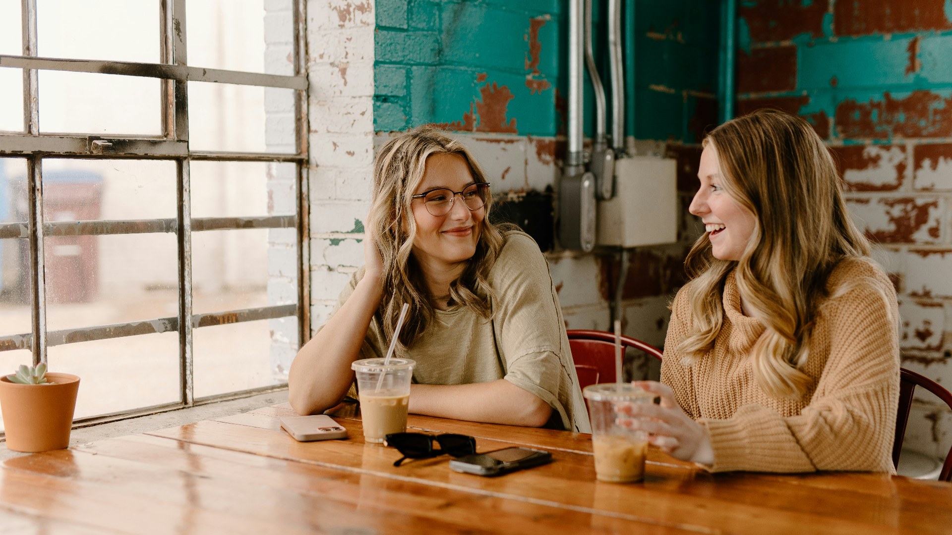 Two women sitting at a wooden table with tense body language