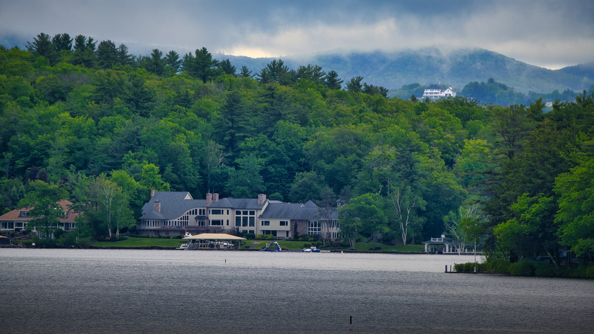 Peaceful scenic view of custom homes and private boat docks along the crystal-clear shoreline of Lake Winnipesaukee in New Hampshire.