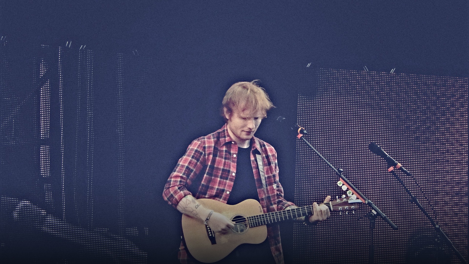 Ed Sheeran performing intensely with acoustic guitar on stage.
