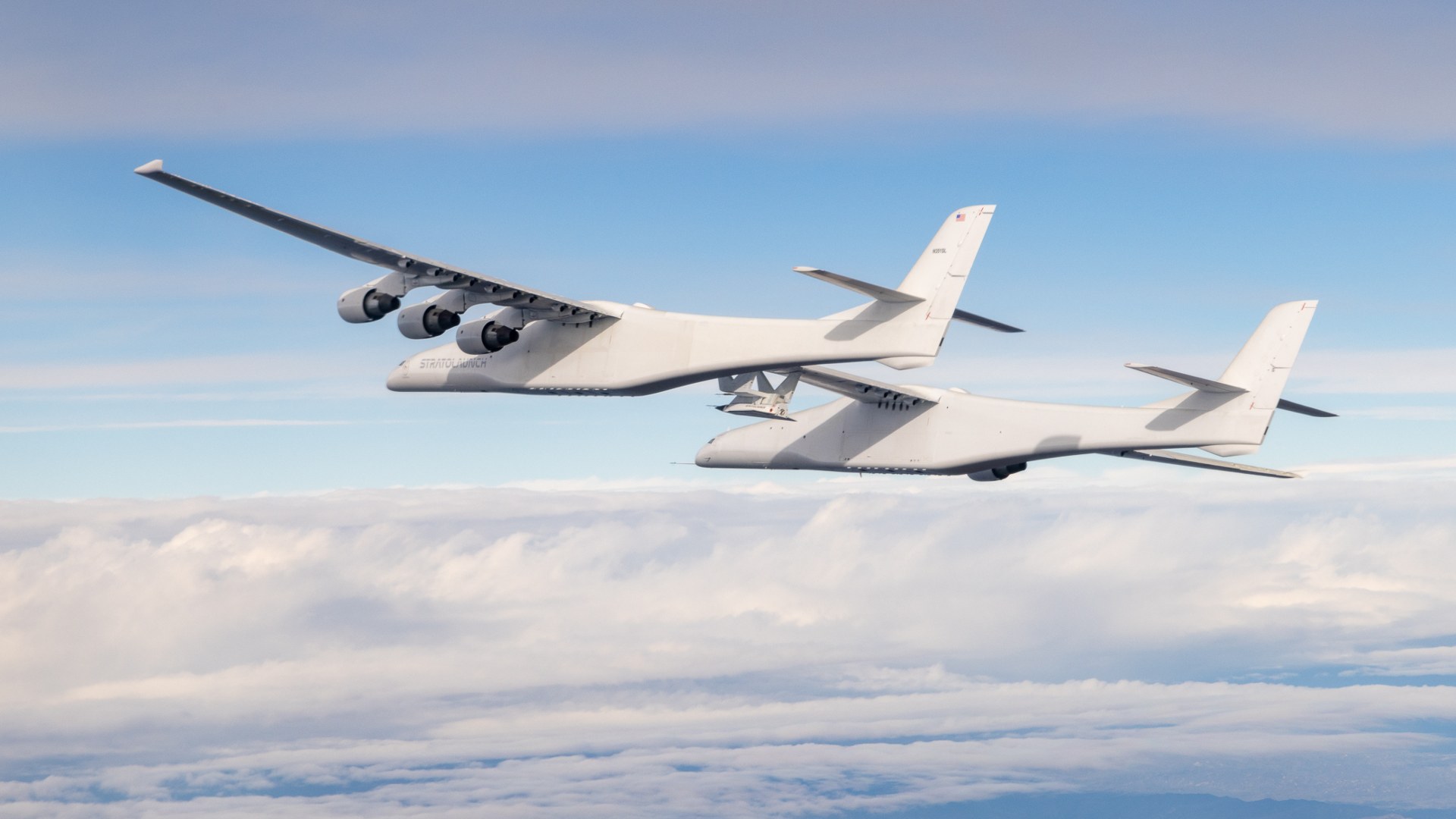 Scaled Composites Model 351 Stratolaunch Roc twin-fuselage aircraft flying above the clouds with a Talon-A hypersonic test vehicle.