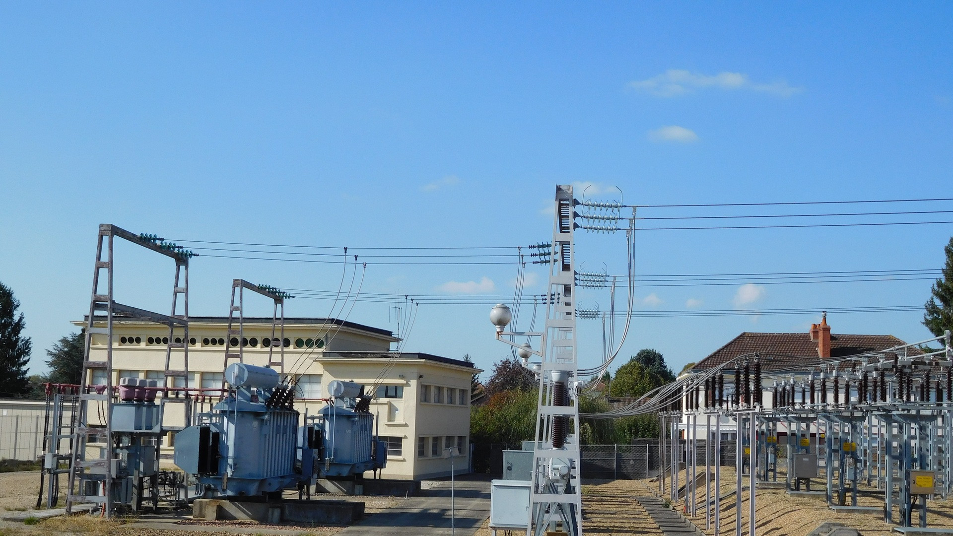 Massive high-voltage power substation transformers and transmission lines beneath a sprawling open sky.