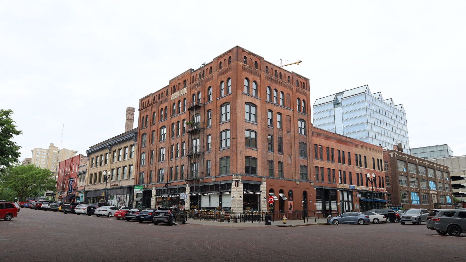 Historic cobblestone and brick street lined with lively restaurants, cafes, and historic brick buildings in the Old Market district of Omaha, Nebraska.