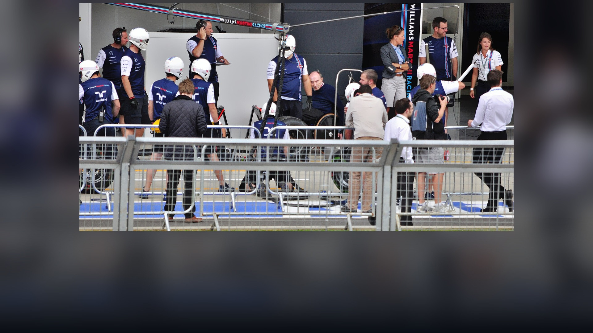 Williams Formula 1 pit crew performing a rapid synchronized wheel-change pit stop.