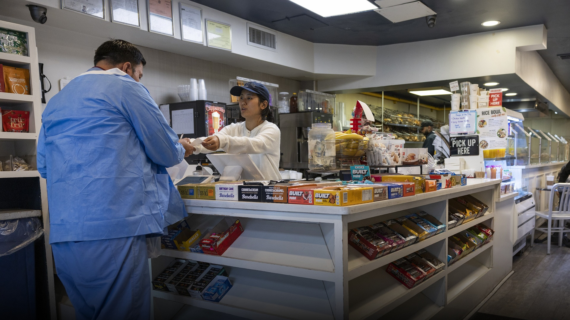 A friendly cashier smiling and engaged in conversation with a customer while handing over a receipt across a counter.