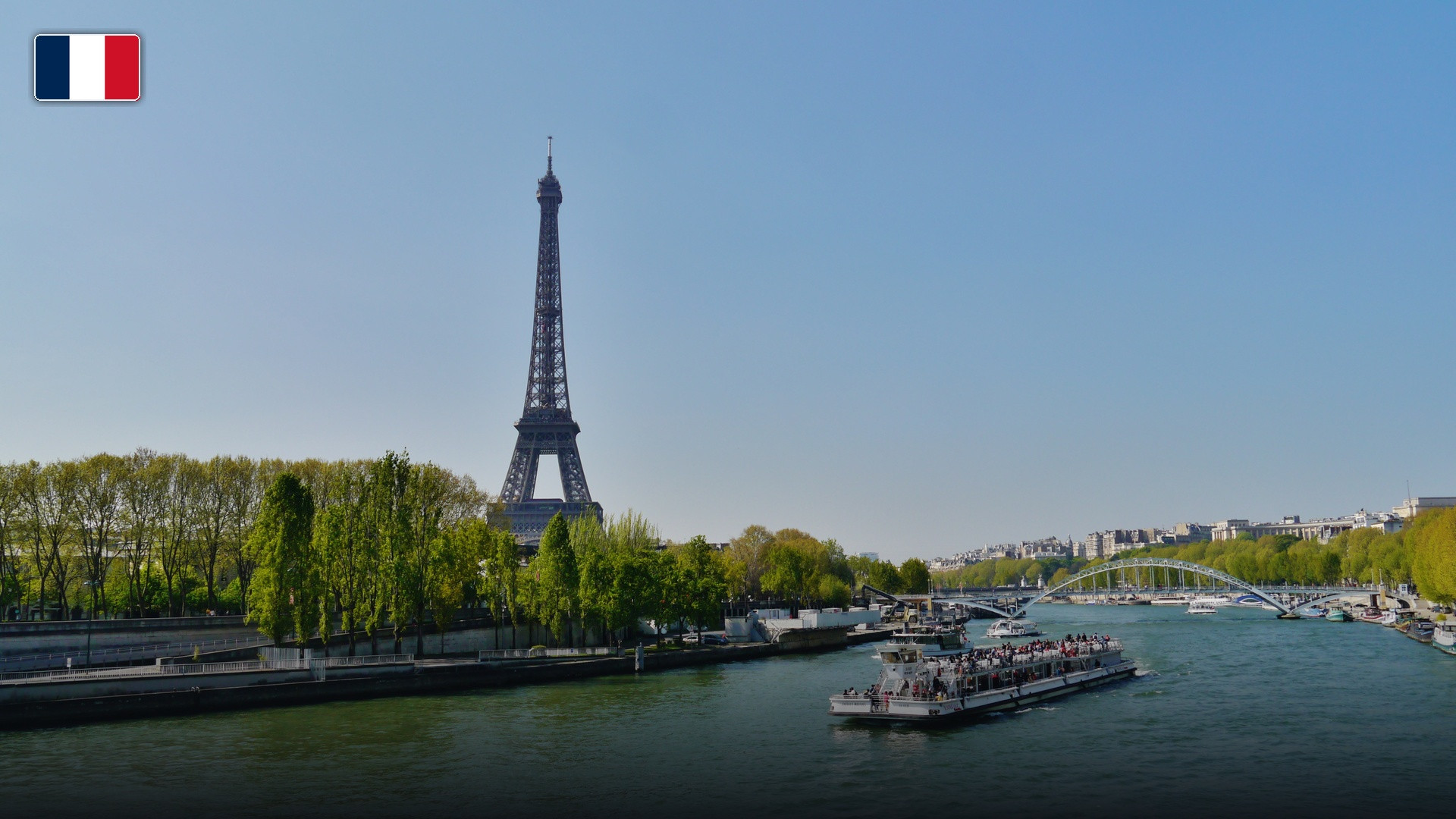 The Eiffel Tower rising majestically beside the River Seine in Paris, with the flag of France.