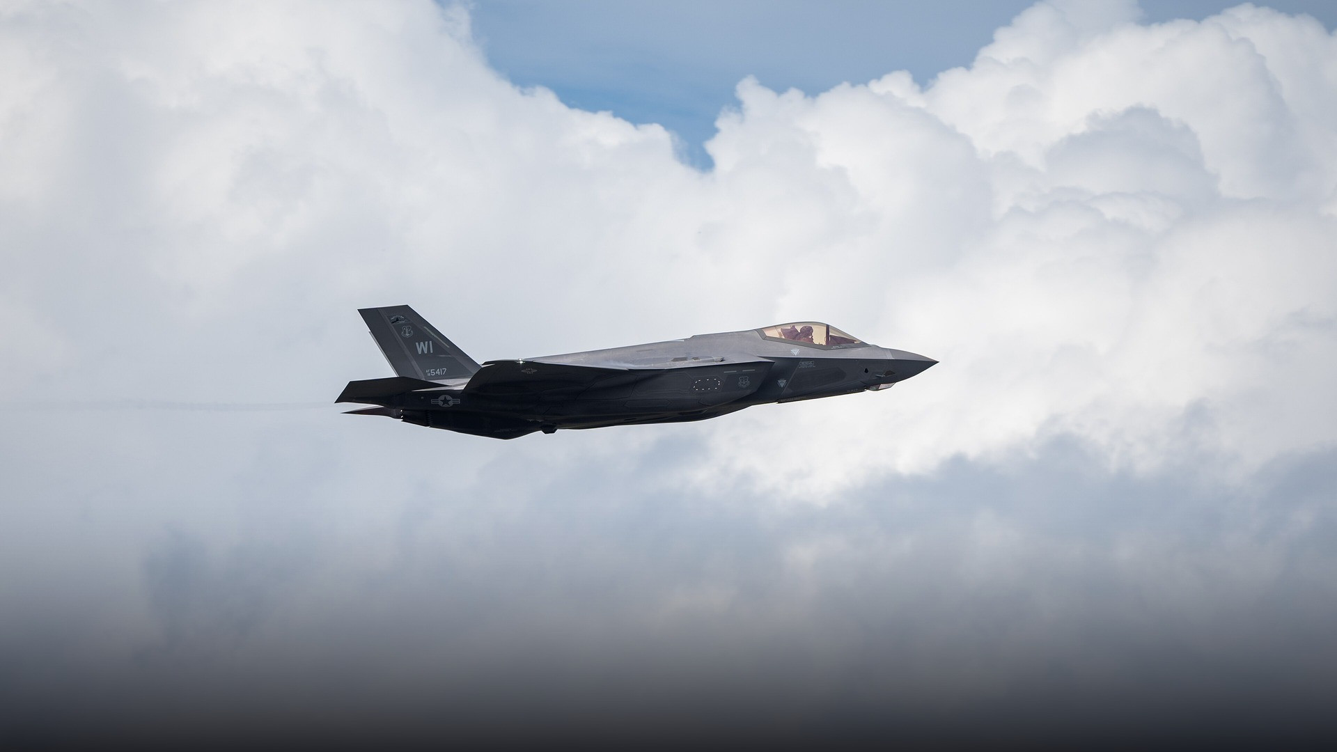An advanced F-35A Lightning II stealth fighter jet banking sharply against the sky.