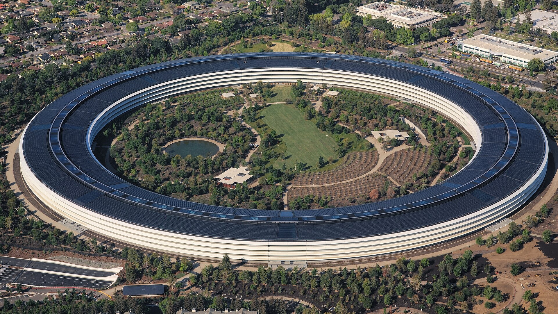 Aerial view of the iconic circular Apple Park headquarters in Cupertino, California alongside CEO Tim Cook.