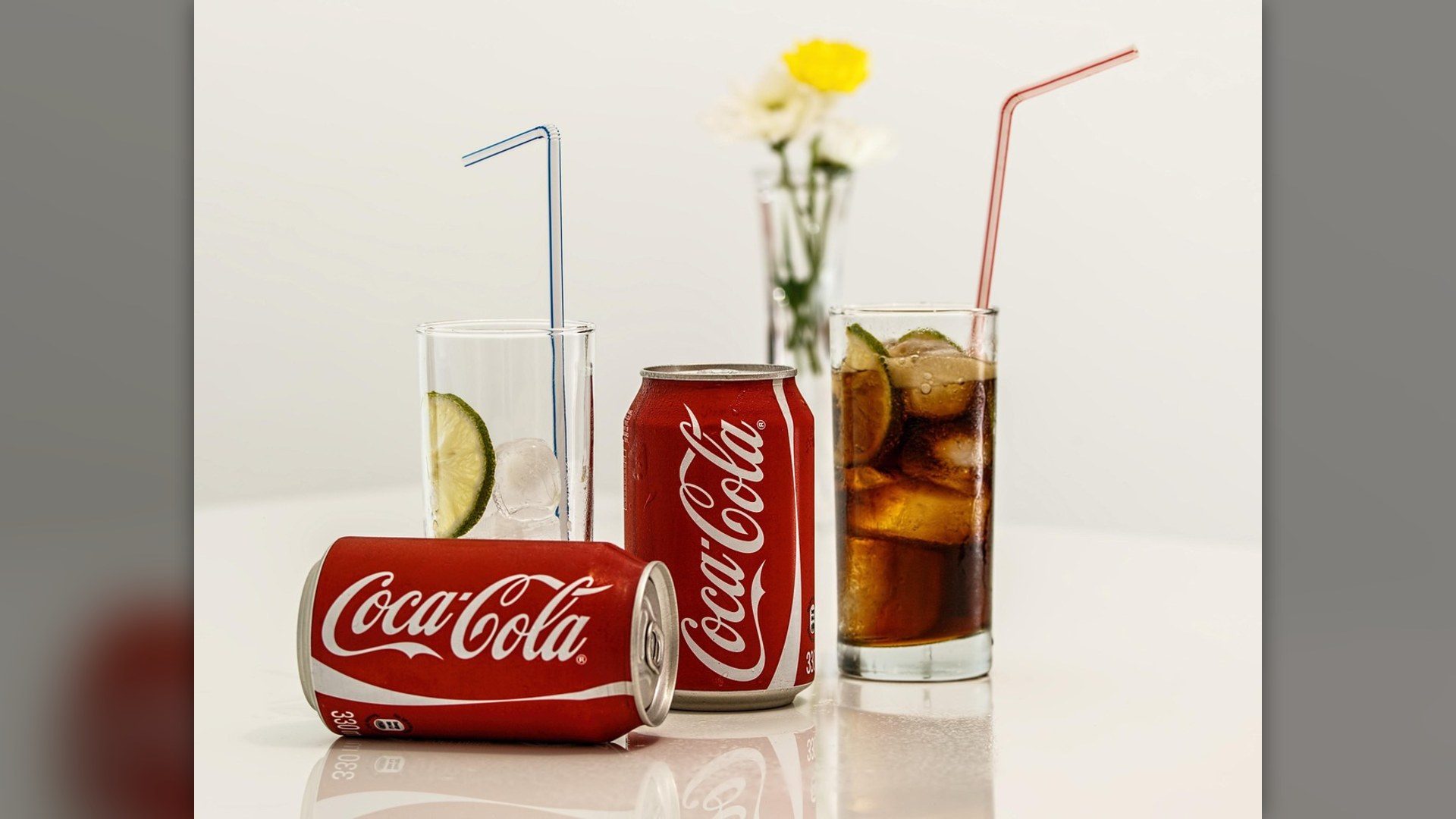 Sugary carbonated soda in glass with ice and cola can