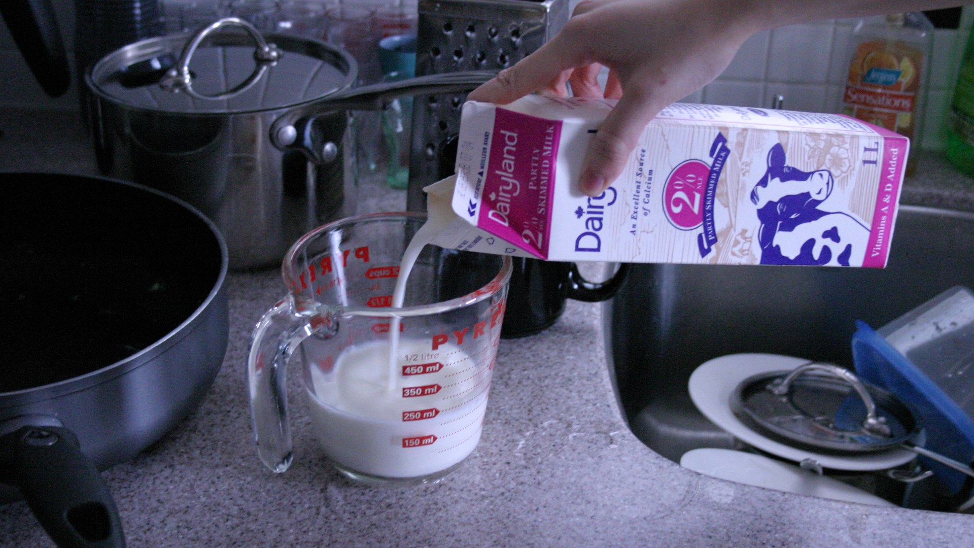 Fresh white dairy milk being poured into a glass pitcher