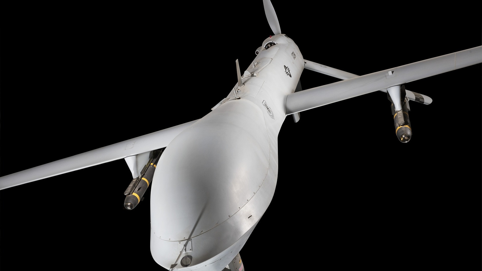 High-altitude unmanned military drone in flight against an open blue sky.