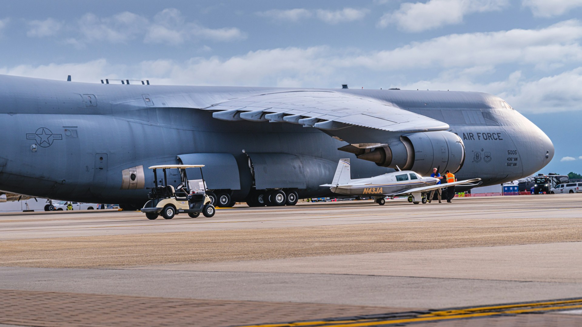 U.S. Air Force Lockheed C-5M Super Galaxy strategic airlifter towering over a civilian jet on the ramp.