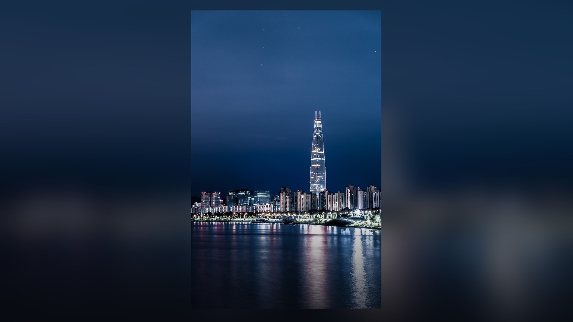 Lotte World Tower illuminated against the nighttime skyline of Seoul.