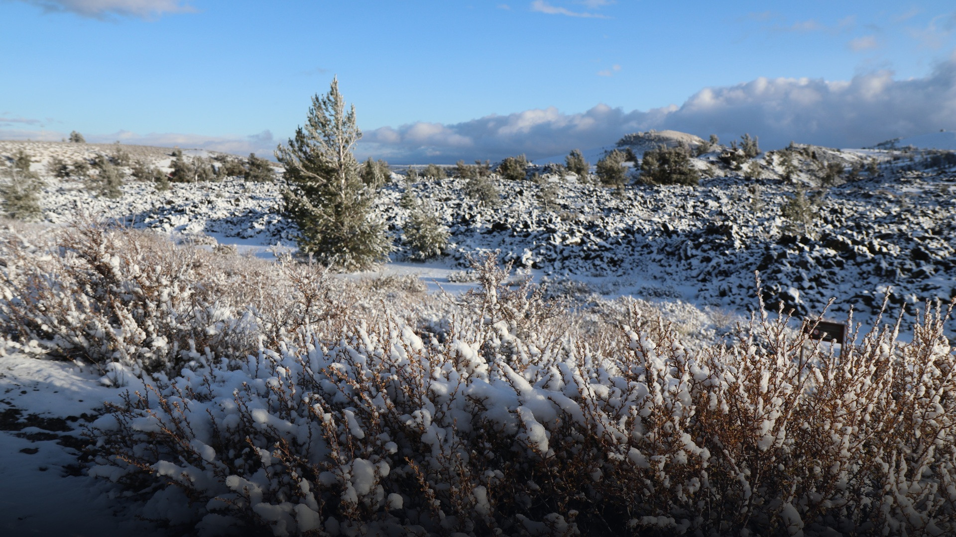 Snow-covered volcanic craters and lava spatter cones across Craters of the Moon National Monument.