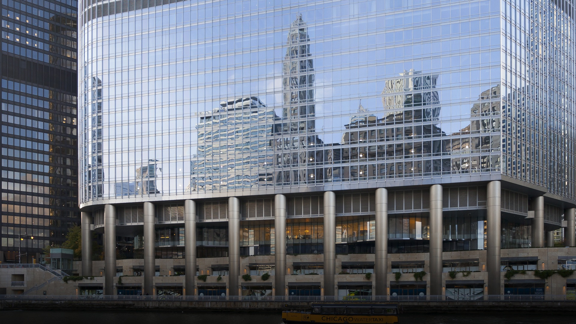 A riverfront perspective of the Trump International Hotel and Tower in Chicago rising above the river bridges.