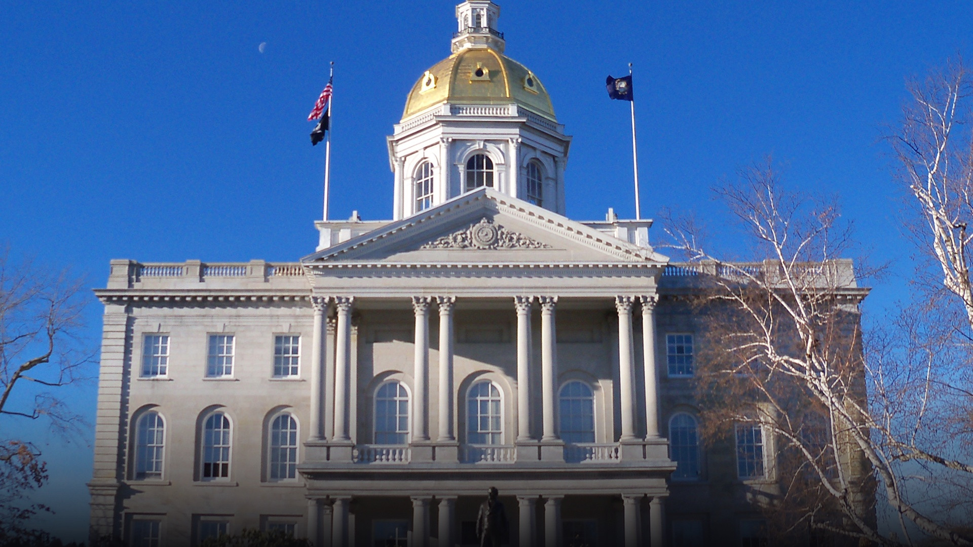 Historic golden dome and granite neoclassical facade of the New Hampshire State House in Concord.