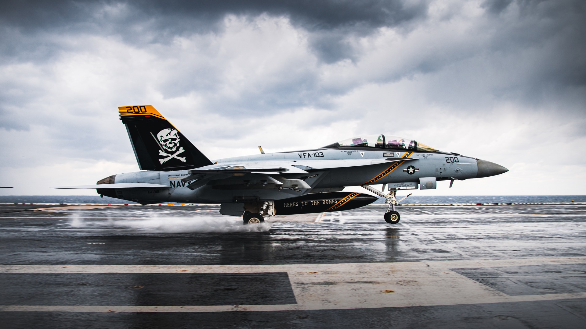 U.S. Navy F/A-18F Super Hornet twin-engine fighter touching down on an aircraft carrier flight deck.