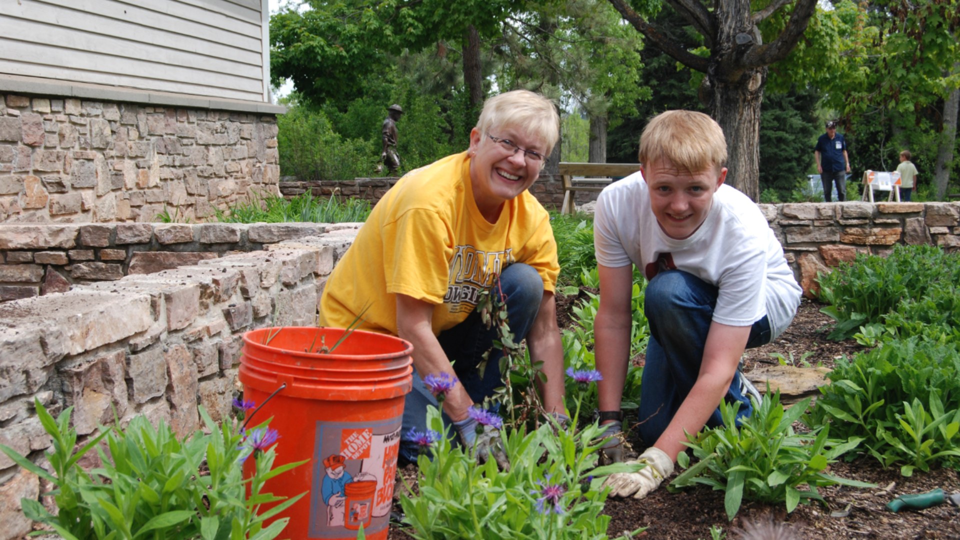 A grandmother and grandson working together in an outdoor garden.