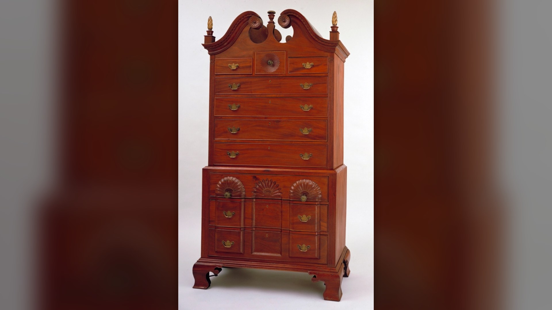 Carved mahogany chest of drawers with ornate brass hardware handles