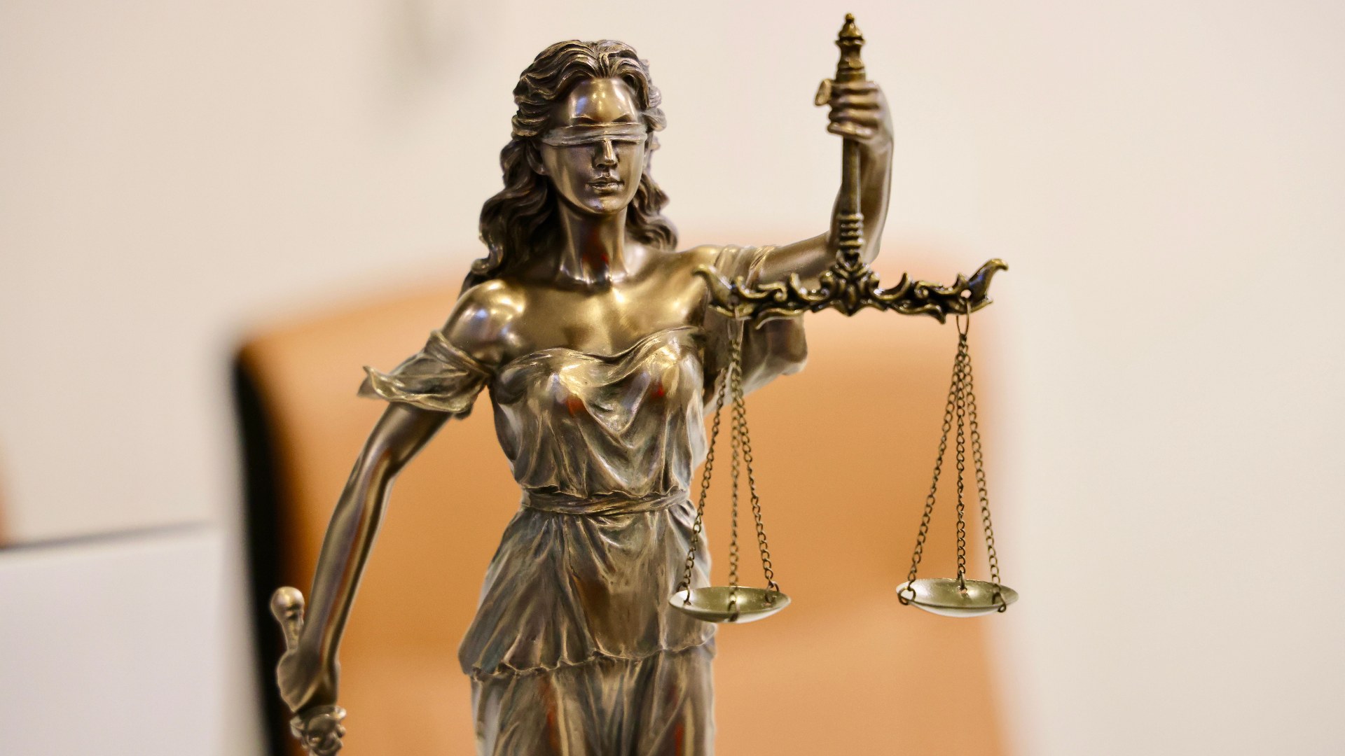 Bronze statue of Lady Justice holding balanced scales in symbolic judgment.