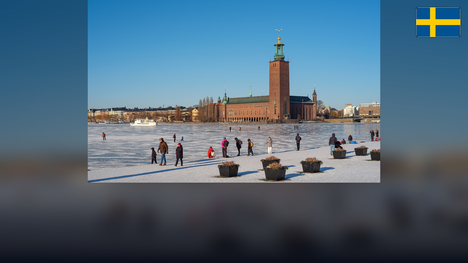 Stockholm City Hall across Riddarfjärden with the Swedish flag in the top right corner.