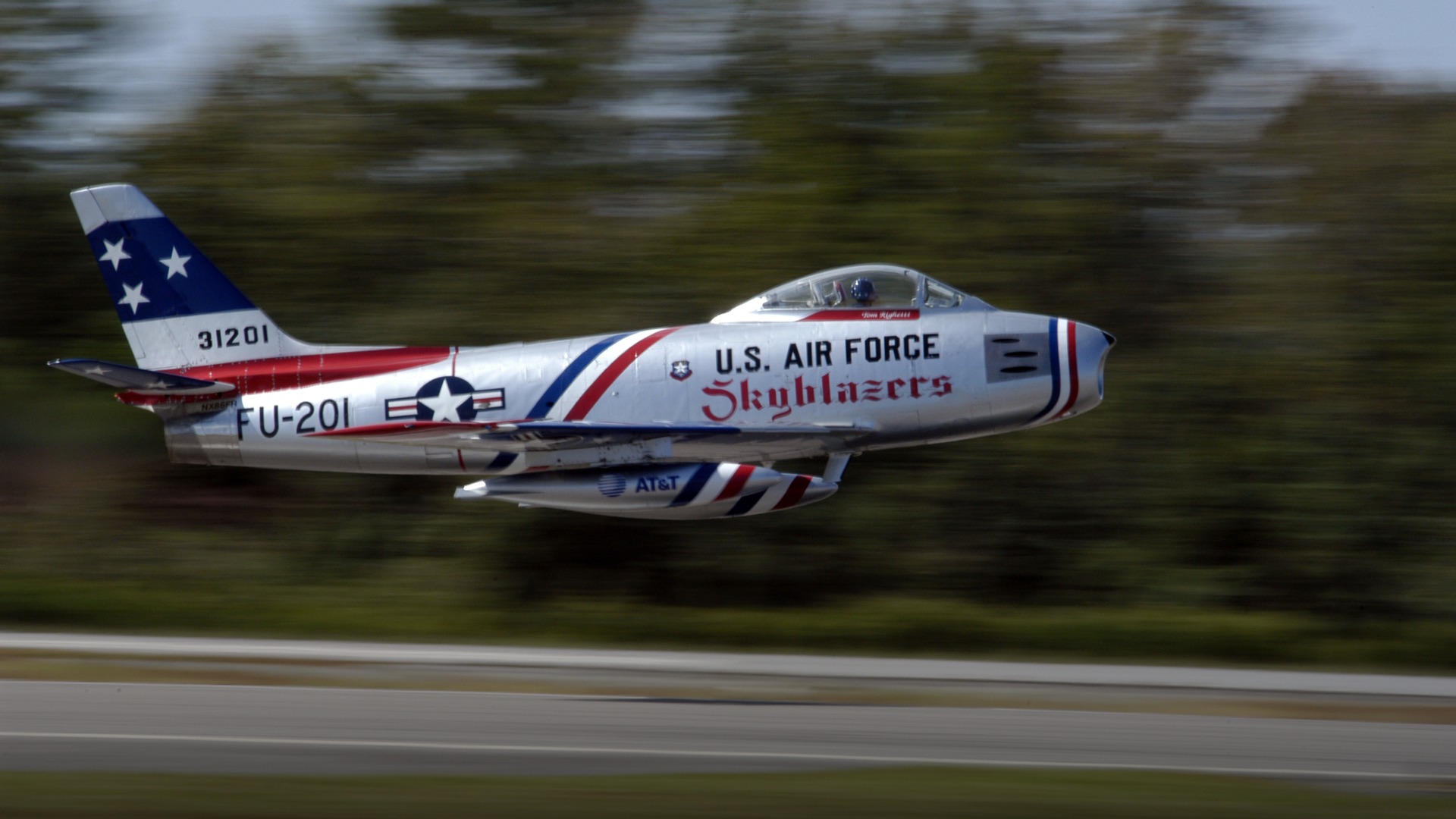 Vintage F-86 Sabre swept-wing fighter jet climbing rapidly after takeoff.