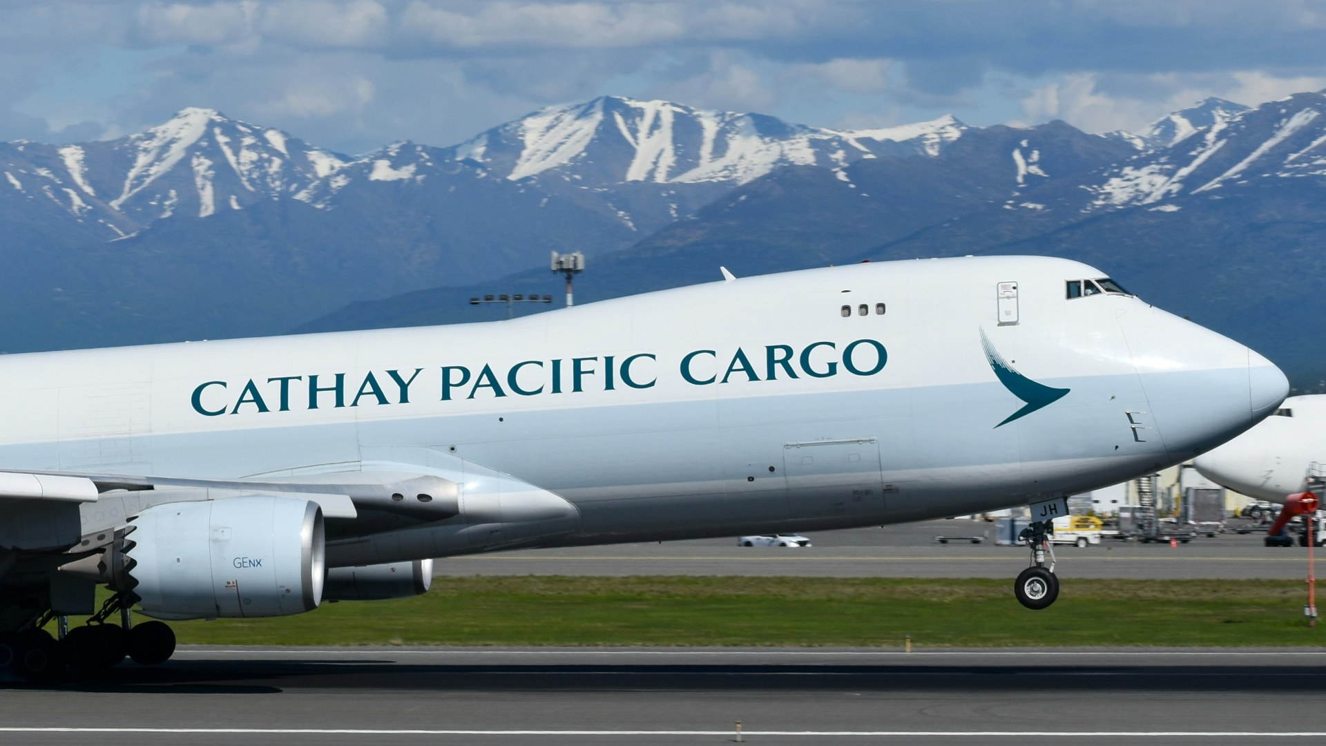 Cathay Pacific Cargo Boeing 747-8F widebody freighter taking off against mountain peaks.