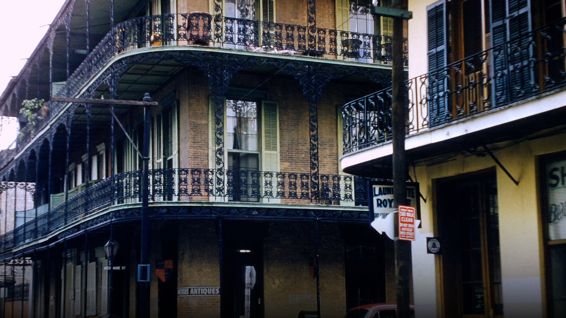 Historic ornate wrought-iron lace balconies and shuttered French Quarter architecture in New Orleans.