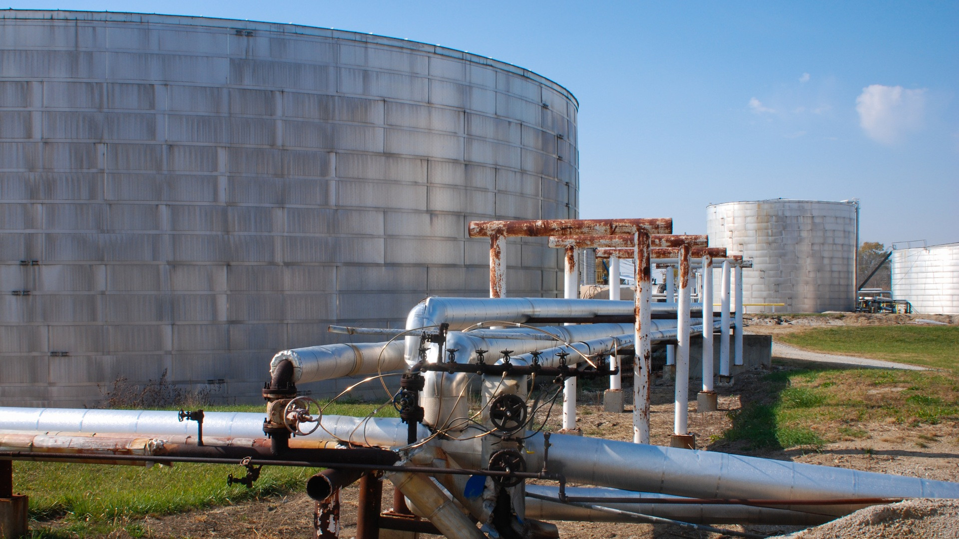 Detailed shot of heavy mechanical valves, pipework, and fuel dispensing apparatus at a distribution depot.