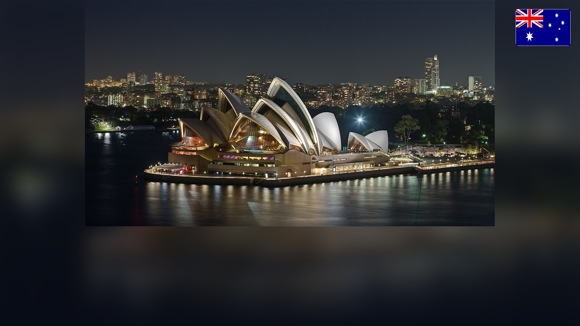 Sydney Opera House in Sydney Harbour with the Australian flag in the top right corner.