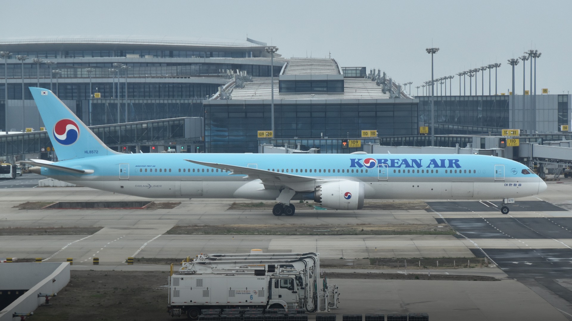 A state-of-the-art Korean Air Boeing 787-10 Dreamliner gleaming in light blue and white livery in flight.