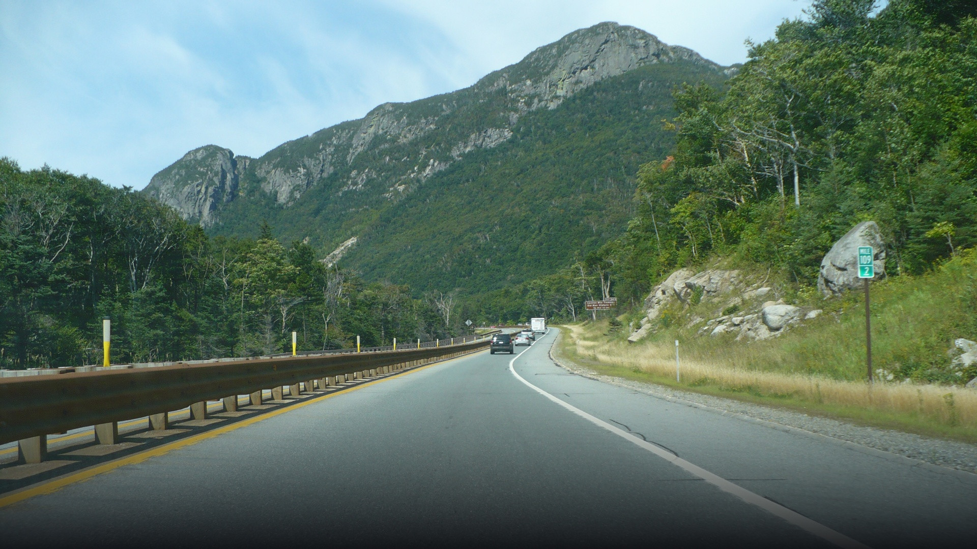 Scenic view of Interstate 93 winding through Franconia Notch surrounded by towering autumn mountain peaks.