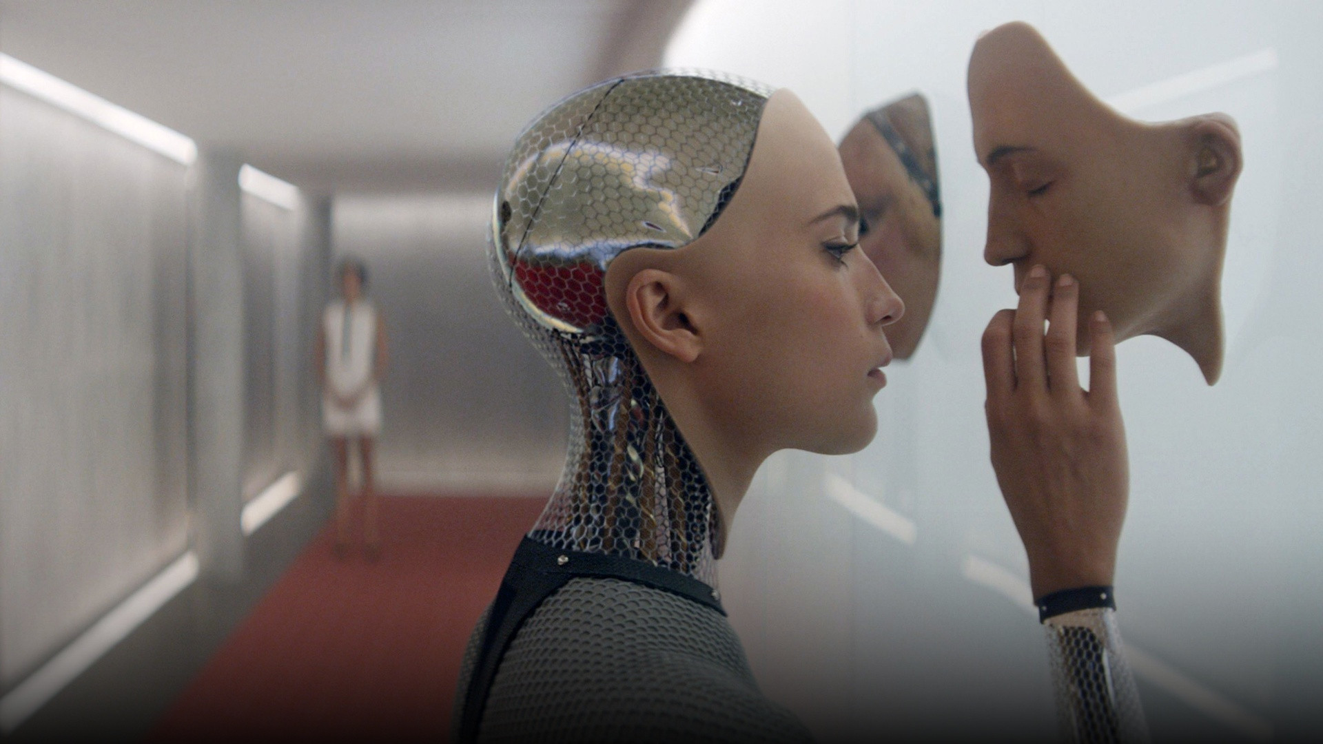 Ava the android examining synthetic facial masks against a sleek glass wall in Ex Machina.