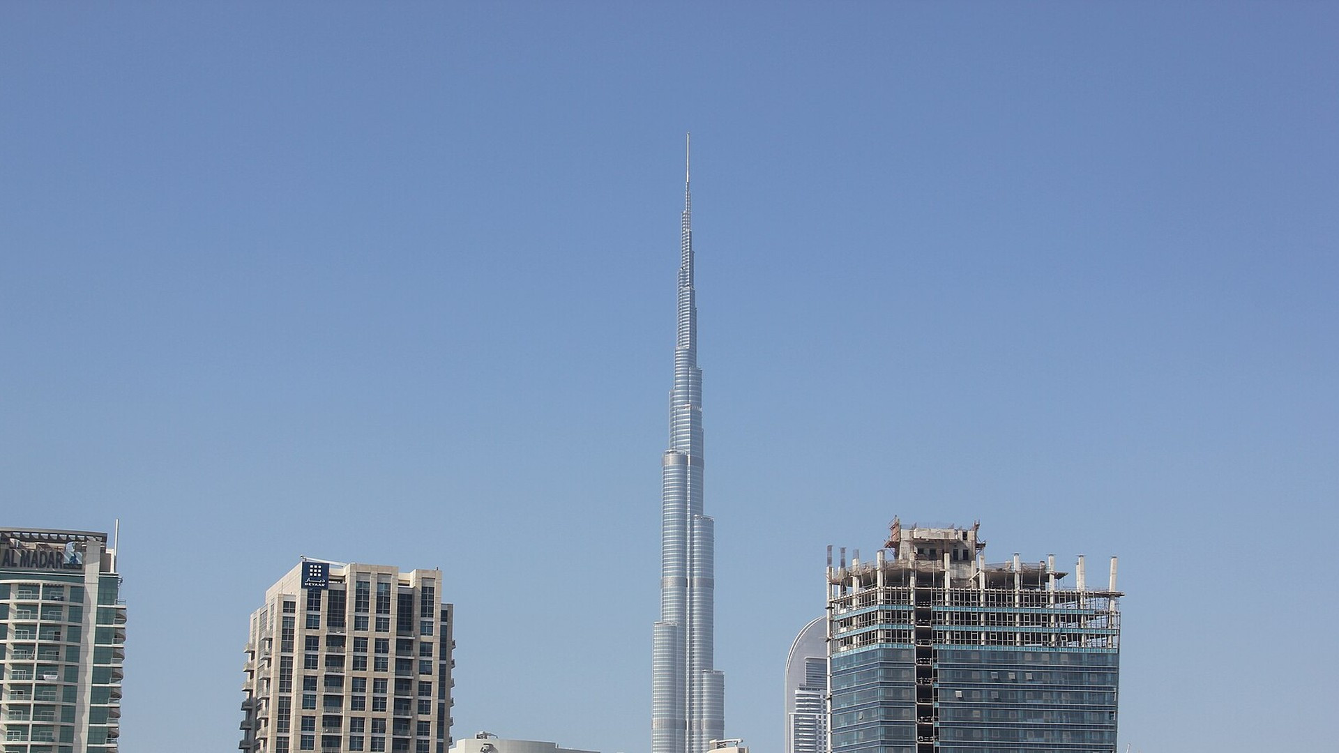 The gleaming spire of Burj Khalifa soaring into a clear blue sky above Downtown Dubai.