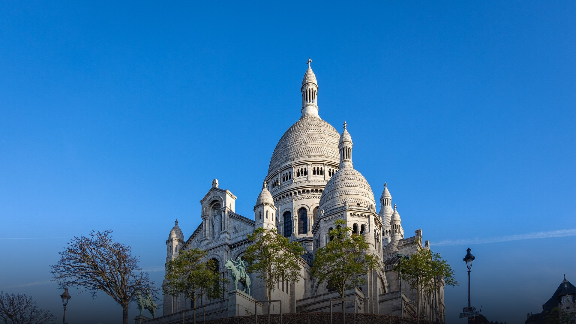 The complete white Romano-Byzantine domes, summit cross, and front elevation of Sacré-Cœur Basilica overlooking Paris.