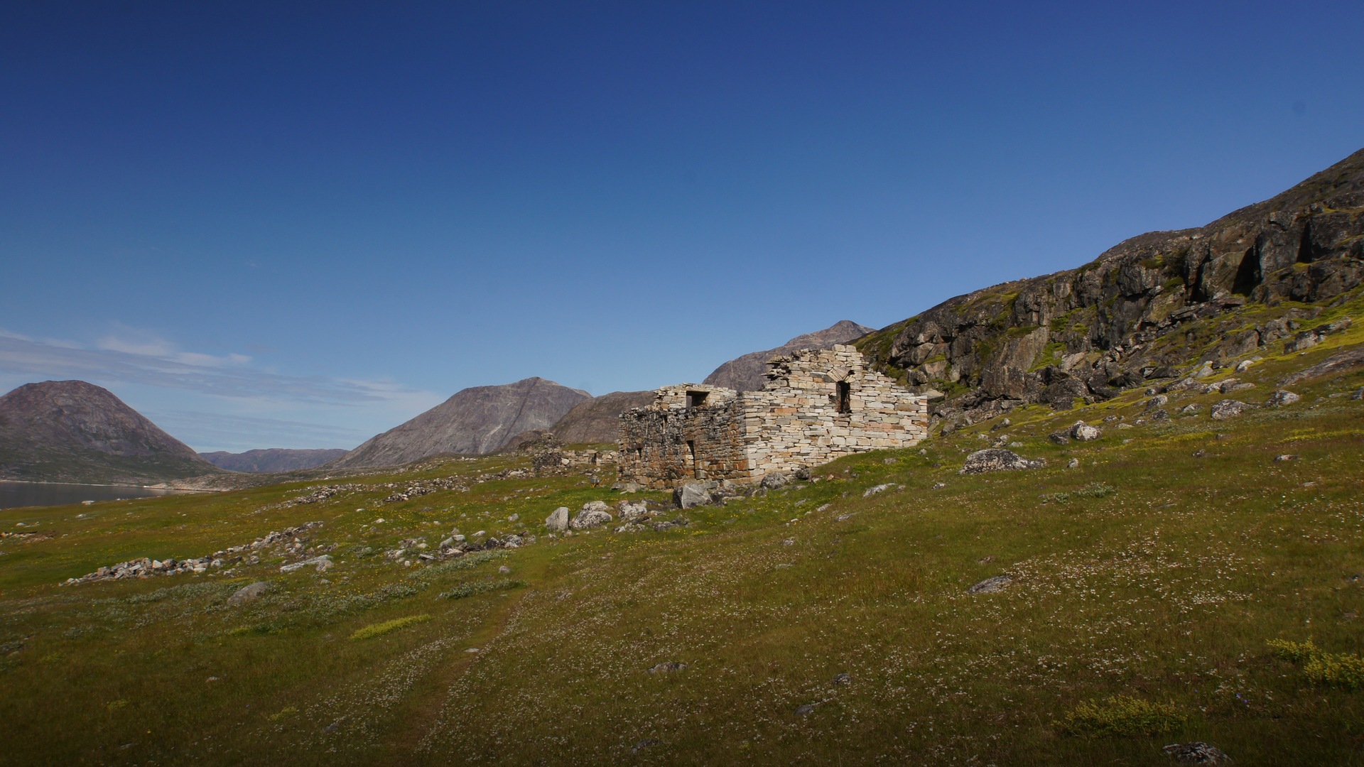 The ancient stone masonry walls of Hvalsey Church standing solitary amid grassy Arctic slopes in southern Greenland.