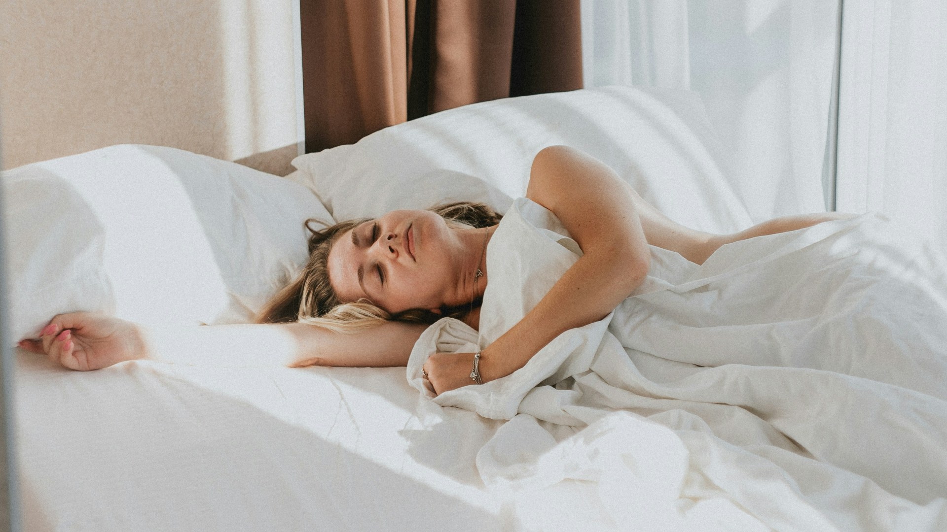 Person lying in bed with legs and feet extended under sheets